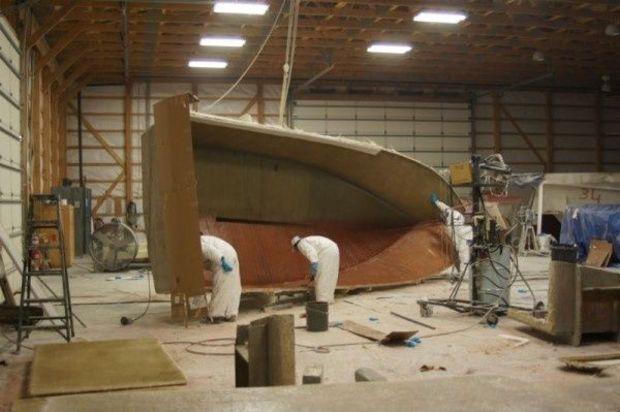 A crew places a layer of fiberglass on the interior hull of a boat as it nears completion. Photo by Gary Reich.