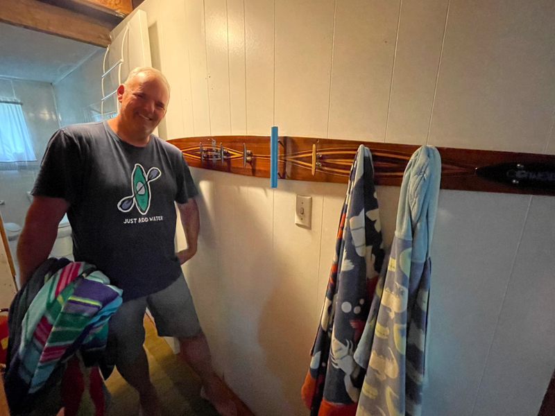 Henn poses with one of the wooden water ski towel racks he created.