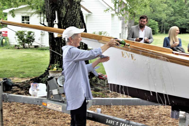 Eve Love christens her namesake, Eve, a 20-foot log canoe, in a launching ceremony held recently in Drayden, MD. Photo by Rick Franke