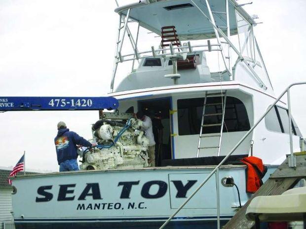The crew at Blue Water Yacht Yard in Hampton removes an engine from Sea Toy.