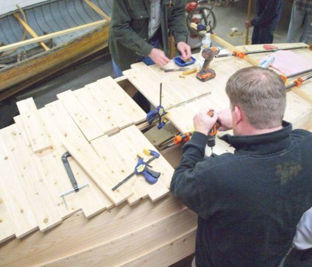 Two students fit bottom planking around the centerboard trunk for the school’s Pretty Good Skiff project. Two students fit bottom planking around the centerboard trunk for the school’s Pretty Good Skiff project.
