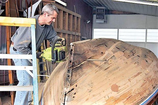 Project manager, Vincent Roe, removes the rotten keel on the log canoe, JAY DEE at Campbell's Boatyard in Oxford, MD.