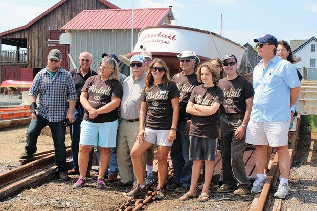 Boat yard program manager Jenn Kuhn (center, with name tag) and some of the Apprentice for a Day volunteers who built Pintail celebrate her launching.