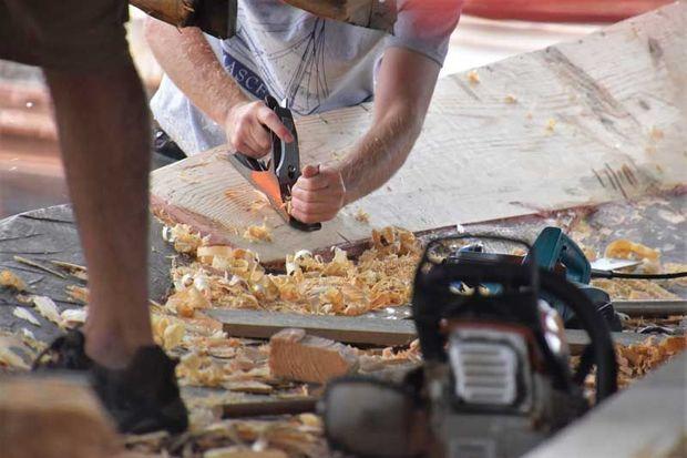 A shipwright at the Chesapeake Bay Maritime Museum in St. Michaels, MD, works on fairing Edna Lockwood’s log pottom in the yard.