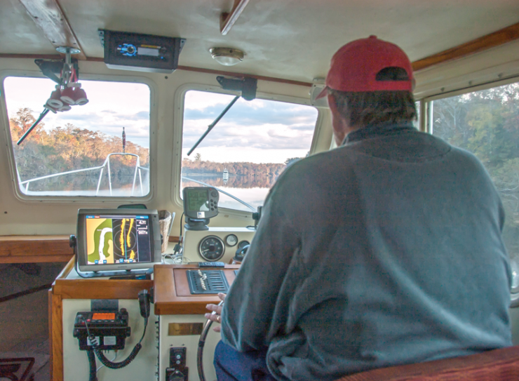 Gene at helm of Early Bird using split screen with radar and chartplotter.