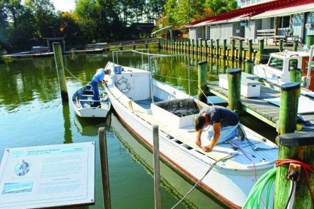 Volunteers Al Rondina (L) and Tony Pettit work on replacement deck planks on a 36-foot Hooper Island Draketail at Calvert Marine Museum in Solomons, MD.Photo by Butch Garren