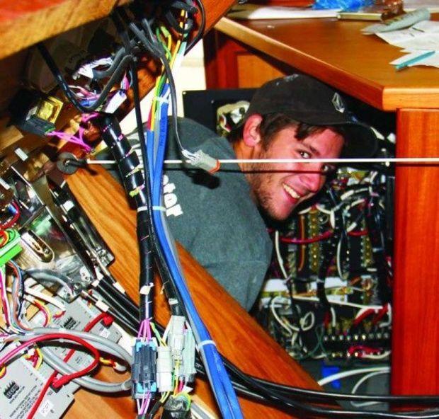 Howell knee-deep in a yacht's electrical system.